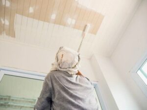 Popcorn ceiling being professionally removed using proper tools and safety procedures