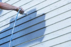 Comparison of spray painting and brush painting techniques used for exterior house surfaces