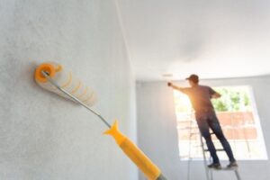 Professional exterior house painter preparing and coating an exterior wall with high-quality materials