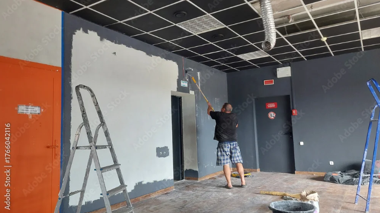 A man painting the walls of a room, demonstrating the work of interior commercial painters.