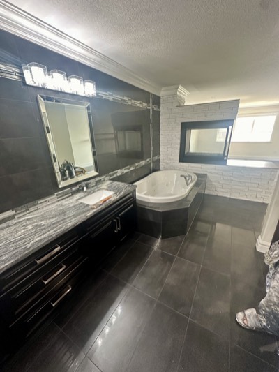 Dark painted bathroom with soaker tub, stone accents, and recessed lighting