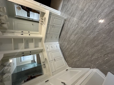 Bright white painted vanity with marble top and frameless mirror