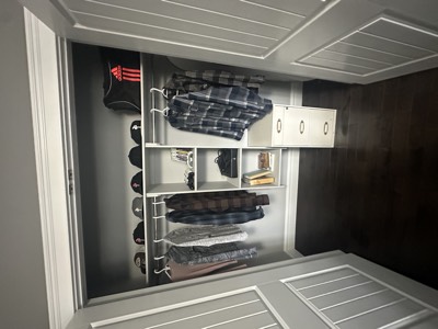 Bedroom closet with dark and white painted shelving and organized storage