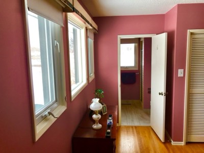 Pink painted bedroom visible through hallway connecting to painted bathroom