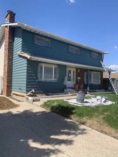 Teal house exterior mid-project showing professional masking and preparation