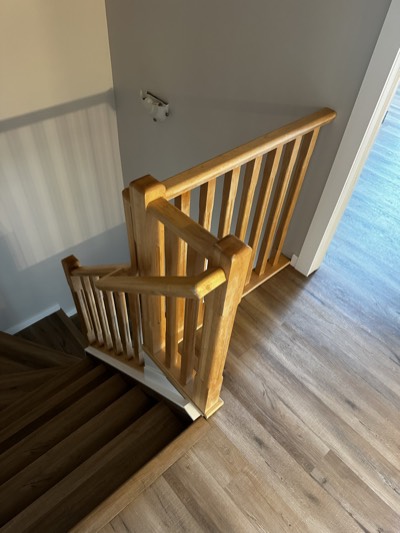 Wood railing with grey painted wall and white trim along staircase