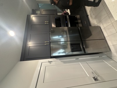 Charcoal grey painted cabinets with white island and stainless steel appliances