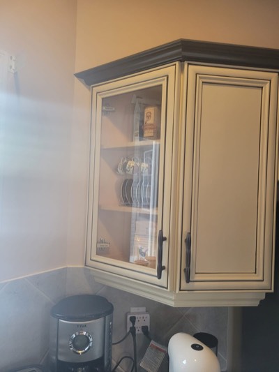 Cream painted kitchen cabinets with glass panel doors and granite countertops