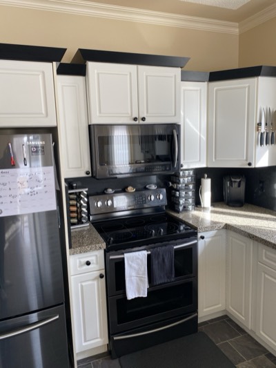 White kitchen cabinets with black crown moulding detail and pendant lighting