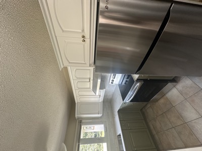 Bright white painted kitchen cabinets with stainless steel appliances and tile backsplash