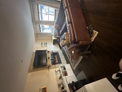 Cozy living room with leather furniture and warm painted walls around stone fireplace