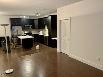 Open floor plan living room connected to dark painted kitchen with island