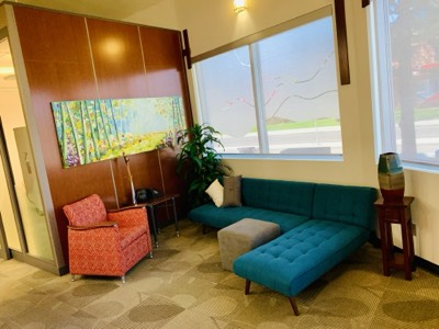 Office waiting area with teal couch and freshly painted neutral walls