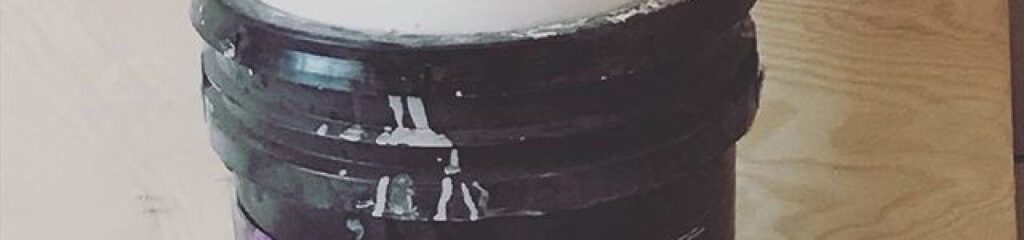 Painter adding paint conditioner to improve flow, leveling, and workability during an interior painting project