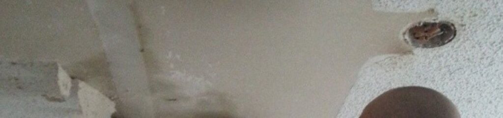 Popcorn ceiling texture being evaluated and removed using proper safety tools and preparation methods