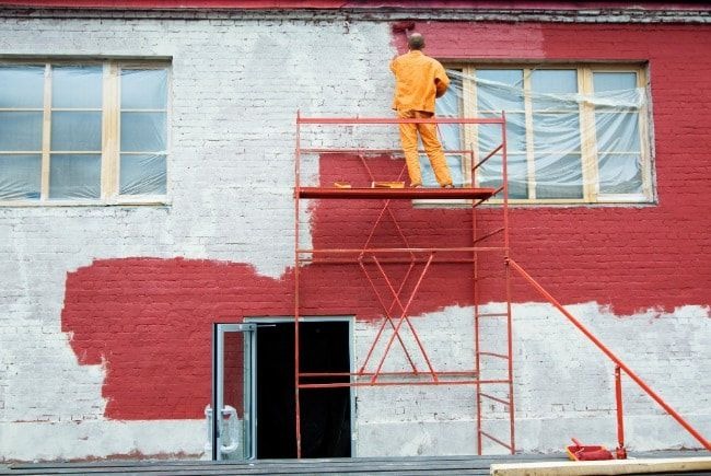 Commercial building receiving professional painting services to improve exterior appearance and structural protection