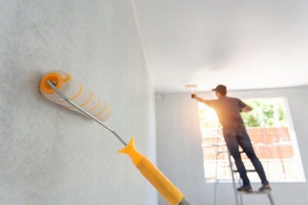 Professional exterior house painter preparing and coating an exterior wall with high-quality materials