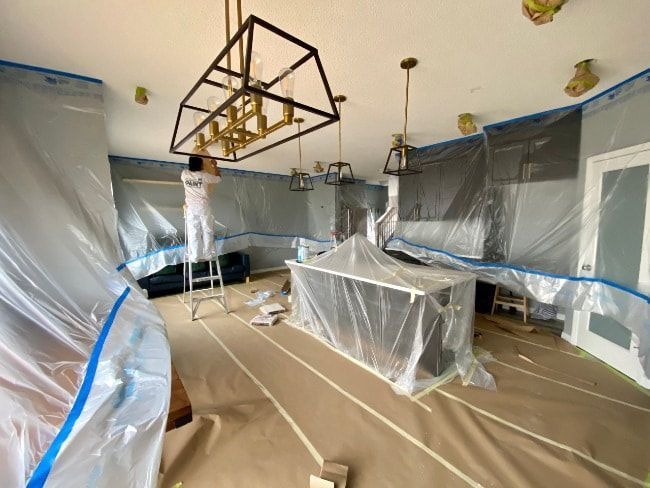 Homeowner or professional painter cleaning, sanding, and prepping interior walls before applying paint